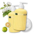 Two pale yellow pump bottles labeled onsensou Double Edge, styled with white flowers, a lime, a sliced lime, and a white circular pad on a white background.