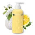 A bottle of Onsensoul Fresh Juice body wash in a pale yellow color with a white pump dispenser, styled with white flowers, a lemon slice, and green leaves on a white background.